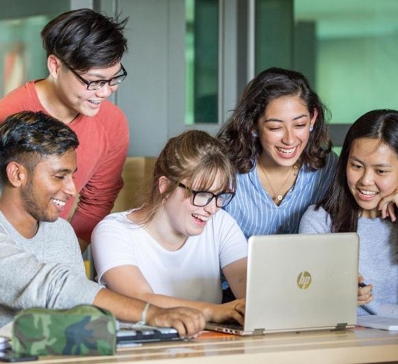 International students collaborating on project with laptop in modern university study space