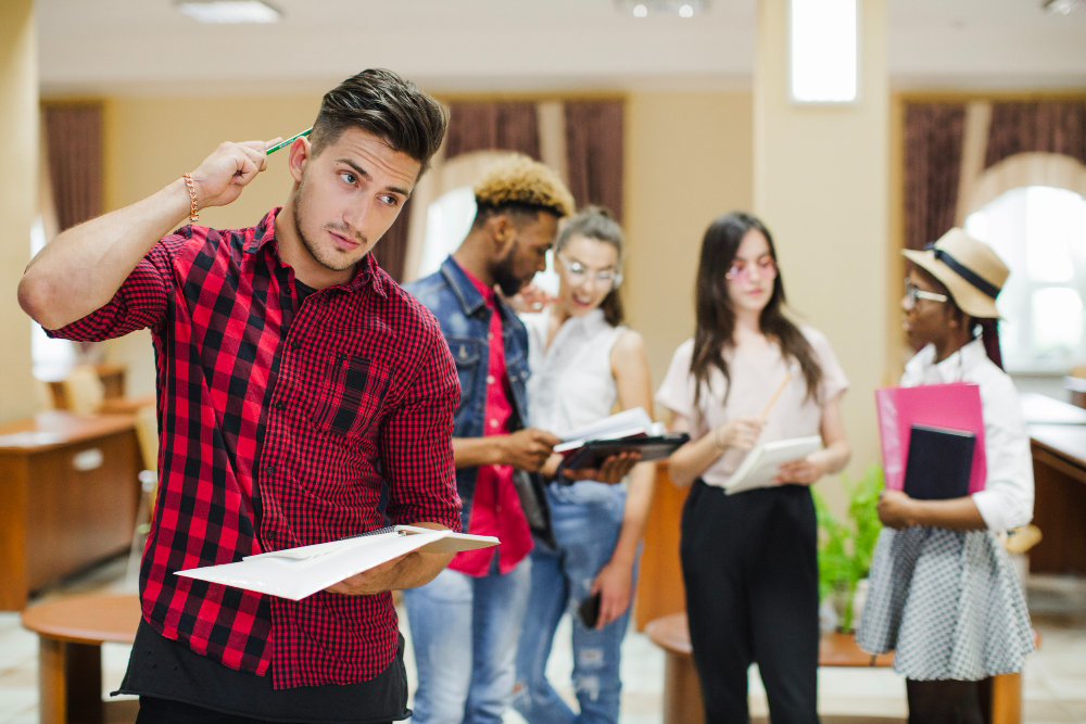 male student in a red flannel shirt thoughtfully reviewing documents while researching how to select the best international university for studying abroad.